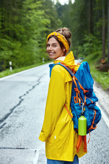 国家女游客在绿林中漫步的垂直镜头冒险模糊雨衣