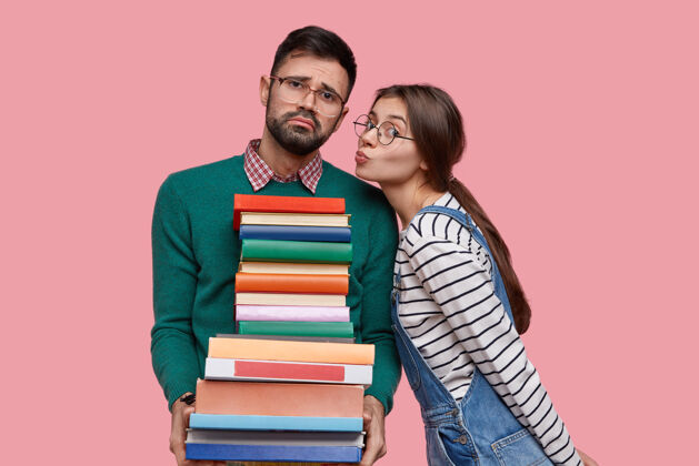 女性可爱的欧洲女学生要吻她的男朋友 她抱着一大摞书 站得很近接吻学习阅读