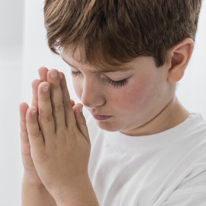 虔诚小男孩祈祷的侧视图信仰广场祈祷