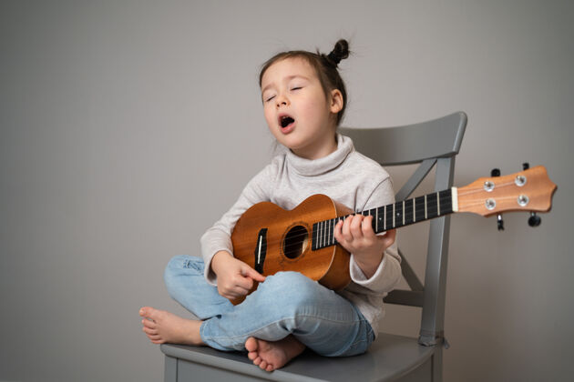 歌曲演奏四弦琴并唱歌幼儿发展美丽的小女孩练习唱歌和弹吉他表情公园音乐家