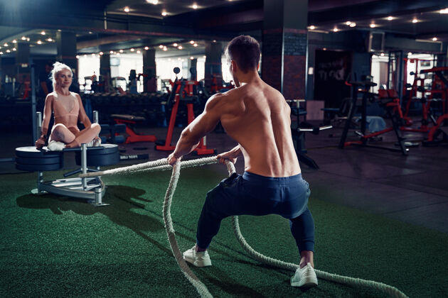 意识健身员在健身房用战绳锻炼努力肌肉训练