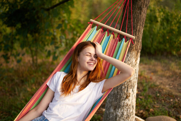 女性快乐的女人躺在户外的吊床上 在森林里笑着笑着模型女人海滩吊床