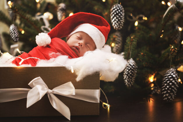 可爱可爱的新生儿戴着圣诞老人的帽子睡在圣诞礼盒里圣诞快乐 新年快乐夜晚小童年