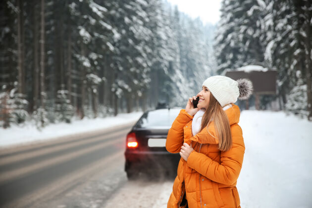 天气在冬季度假胜地 一个年轻的女人在马路边打电话人自然雪