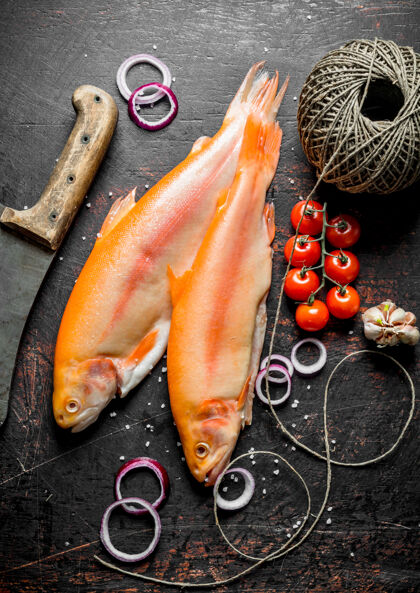 膳食用旧麻绳和刀子在深色的乡村桌子上做生鳟鱼海鲜顶视图淡水