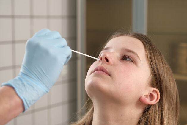 年轻人医生的手拿着棉签 从一个女孩的鼻子里取出一份分析报告女孩测试大流行