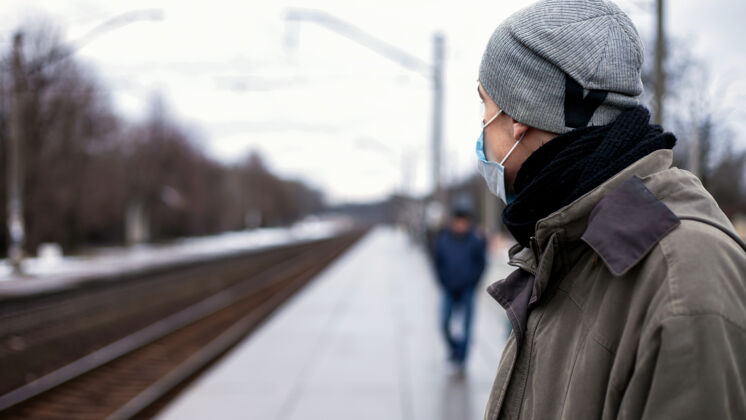 姿势戴口罩的人在等火车概念：感冒 流感 冠状病毒呼吸器病毒防护男性