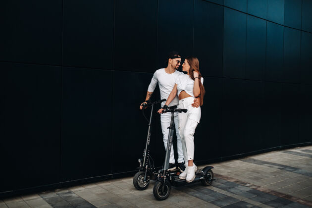 骑一个女孩和一个男孩骑着电动滑板车在城市里走来走去 一对恋人骑着滑板车电力关系驾驶