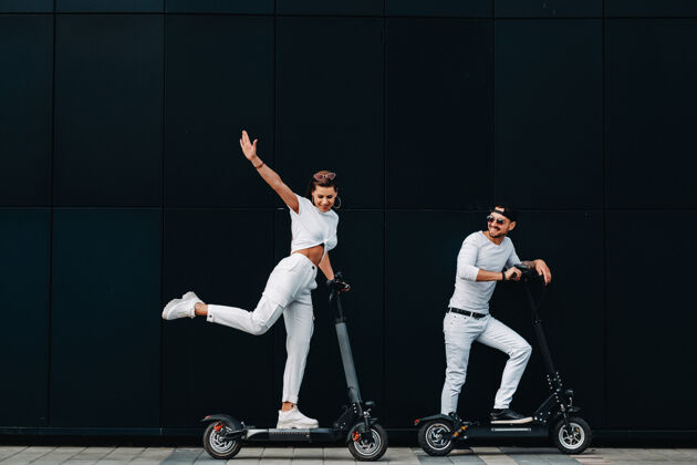 休闲一个女孩和一个男孩骑着电动滑板车在城市里走来走去 一对恋人骑着滑板车家伙街道驾驶