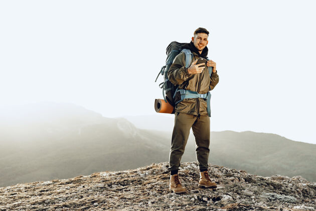 顶部年轻的高加索男子背着大背包在山上徒步旅行站立旅游冒险