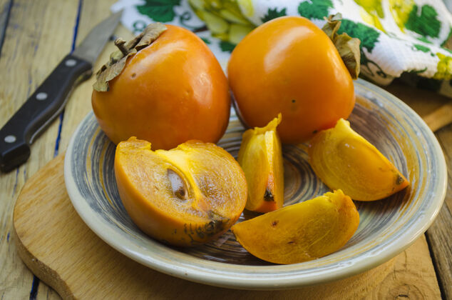 小吃成熟的柿子放在木桌上的盘子里多汁的东方饮食