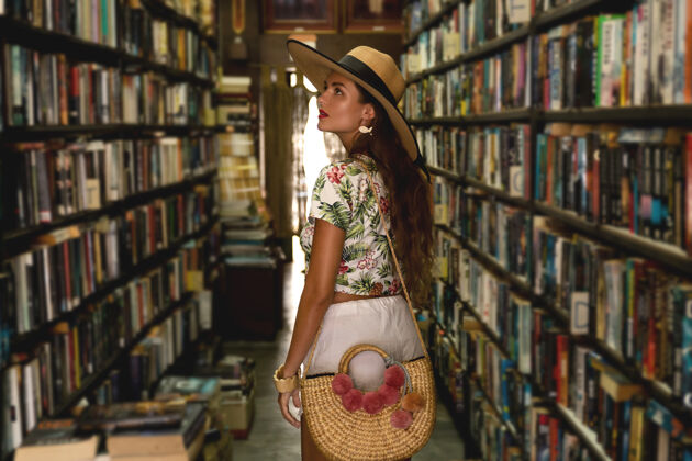 配件穿着时髦服装的漂亮女孩在老式小书店里寻找有趣的书概念短裤肖像