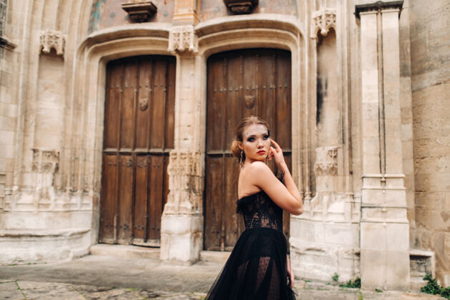 华丽一位身着黑色婚纱的时尚新娘在法国古城阿维尼翁摆出姿势穿着漂亮的黑色连衣裙的模特在普罗旺斯拍照肩膀女孩宫殿