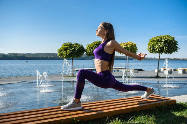 模特运动型身材的女人白天在湖边练瑜伽健美操姿势生活