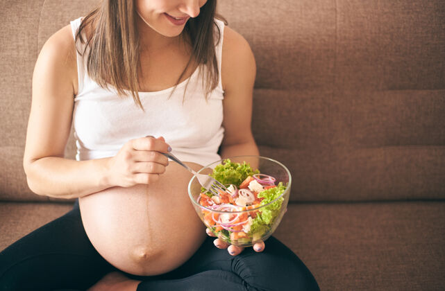 蔬菜孕妇在家吃新鲜沙拉的正面图年轻产妇出生