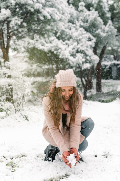 高兴快乐的女人穿着暖和的衣服坐在雪堆里的树林里 享受冬天的周末雪积极享受