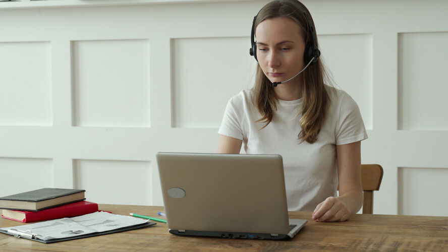 搜索女接线员在呼叫中心使用耳机和笔记本电脑网络空间实习生学习