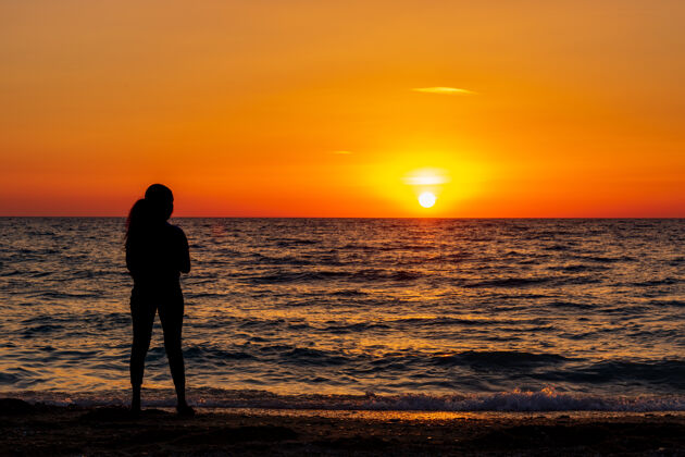 护理孤独的女人站在沙滩上日落人健康安静