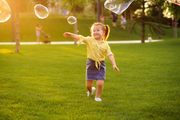 阳光快乐的4-5岁小女孩在公园里玩肥皂泡孩子们的生活方式太阳自然小