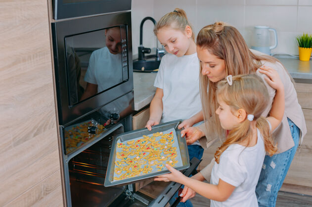 姐姐妈妈教她的女儿们在厨房做饭女人父母室内