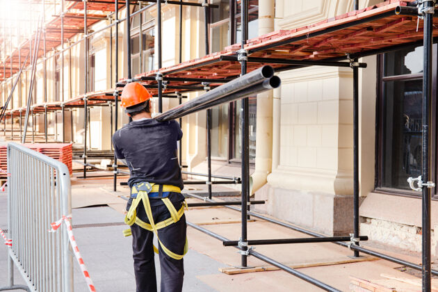 柱建筑工人肩上扛着一根钢梁施工现场 建筑施工及改造过程Diy结构钢筋