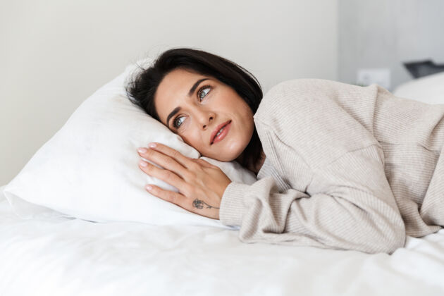 室内30多岁的中年妇女躺在床上 躺在家里的白色枕头上成熟舒适公寓