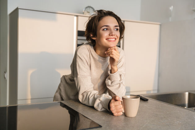 饮料微笑的年轻女子早上在厨房喝茶杯子温暖早餐