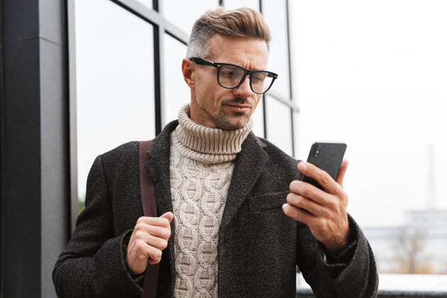 成熟30多岁的留胡子男人戴着眼镜 穿过城市街道 用手机街道电话男人