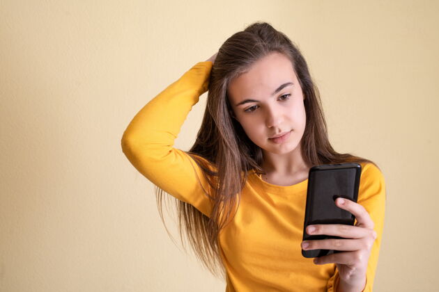 浪漫年轻女子用黄色背景的手机拍照新闻社交兴奋