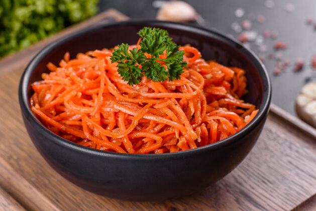 辛辣美味 辛辣 多汁 明亮的韩国胡萝卜 放在深色水泥上的陶瓷盘子里背景.亚洲人美食晚餐韩国人大蒜