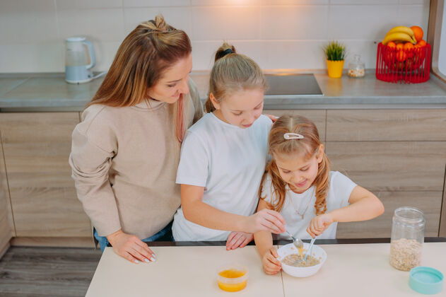 玉米一位母亲和她的两个女儿在厨房里给燕麦片加蜂蜜厨房妈妈债券