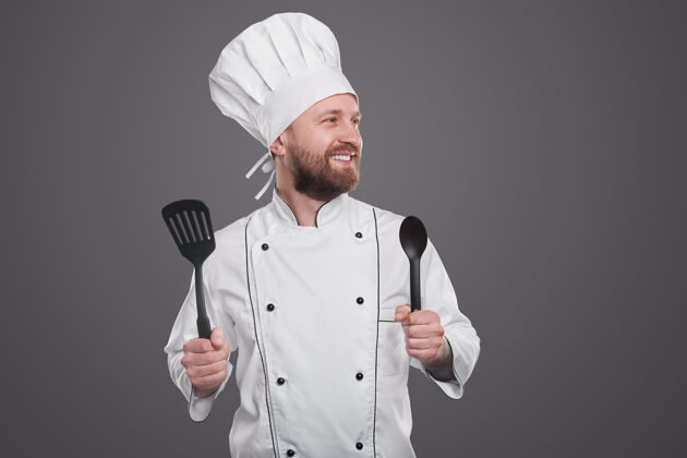 勺子正面胡须男厨师身穿白色厨师制服 手持抹刀和勺子 站在灰色背景下望向别处食物胡须厨房