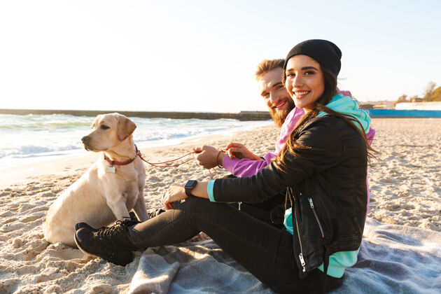 配对可爱的年轻夫妇在海滩上玩他们的狗成人风格浪漫