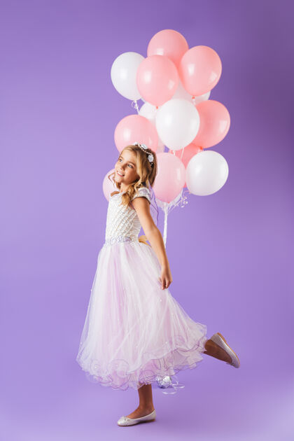 完整一个穿着公主裙的漂亮小女孩孤零零地站在紫罗兰色的墙上 手里拿着一堆气球吸引力公主肖像