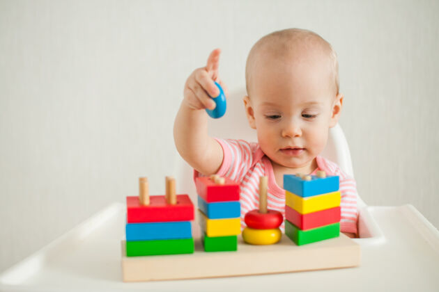 童年小女孩玩着一个教育玩具——一个五颜六色的木制玩具金字塔发展太好了兴趣颜色创意