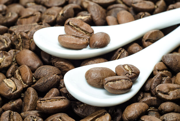 酿造咖啡豆放在烤制咖啡背景上的陶瓷勺子里谷物瓷器