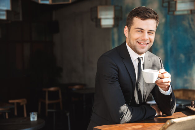 企业家一个英俊快乐的年轻商人坐在咖啡馆喝咖啡的形象事业吸引力英俊