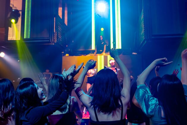 音乐一群人随着舞台上dj的音乐节拍在迪斯科夜总会跳舞夜晚青年音乐会