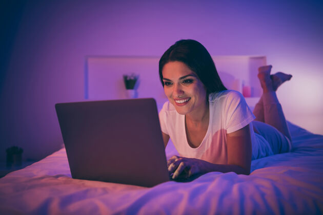 舒适熟女躺在床上用笔记本电脑聊天的写真睡衣打字睡眠