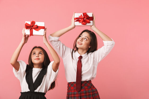 积极身着校服 手持礼品盒 与世隔绝地站在红墙上的快乐女孩的画像青少年年轻快乐