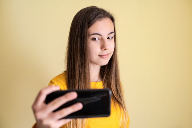 女士年轻女子用黄色背景的手机拍照兴奋学生长度
