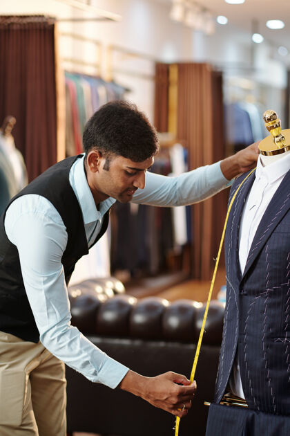 商业年轻的印度裁缝用卷尺量西装外套的正面印度人职业时尚