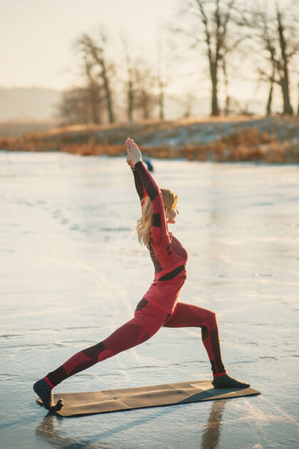 医学冬天 一个女孩在日落时在湖边的冰上做瑜伽健康寒冷湖