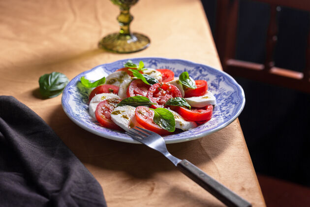 地中海卡普列塞沙拉意大利菜新鲜西红柿 马苏里拉奶酪和奶酪沙拉罗勒黑和穆迪风格的照片 垂直安提帕斯托菜肴开胃菜