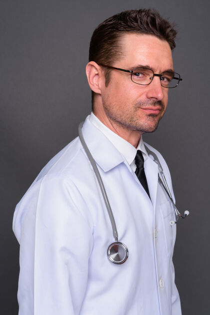 头长着胡子的帅哥医生戴着眼镜靠着灰墙胡茬听诊器胡子
