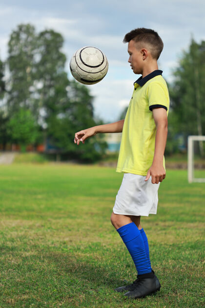 球员穿着黄色t恤的帅哥足球运动员在足球场上玩杂耍游戏领域欢乐