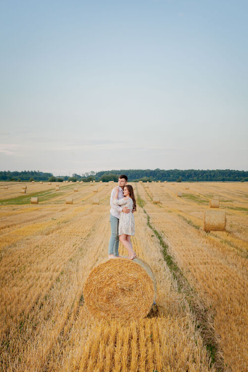 草地稻草上的幸福小两口 浪漫的人的概念 美丽的风景 夏日的季节风景年轻女孩
