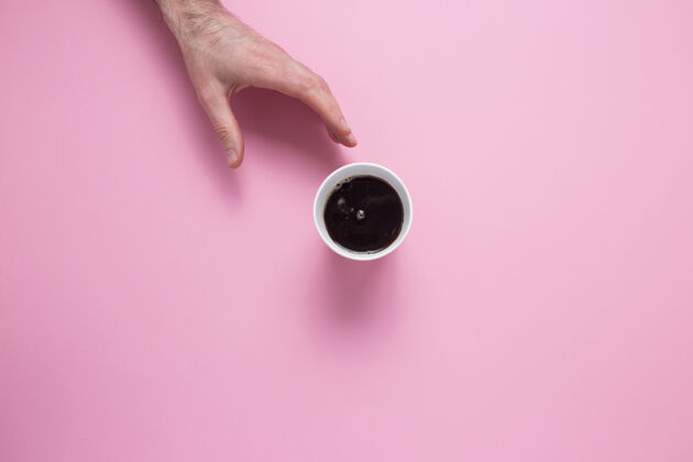 玻璃一只雄性的手伸手去拿一杯粉红色的咖啡董事会咖啡饮料