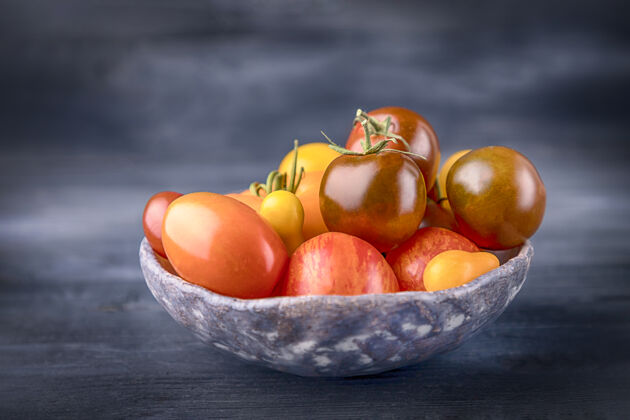 食物在深色木头上放着各种颜色的西红柿的陶瓷碗碗西红柿木头