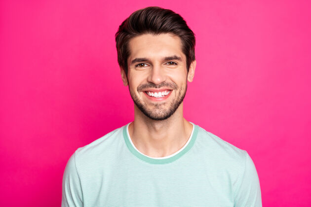 T恤特写照片的黑发惊人男子汉揭示完美的白色牙齿穿休闲t恤孤立的充满活力的粉红色背景微笑漂亮梁